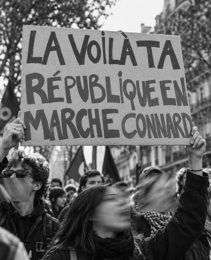 Photo en noir et blanc d'une pancarte des manifs lycéennes d'octobre 2026: "La voilà ta République en Marche connard"