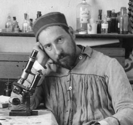 Ramon y Cajal, homme barbu d'une quarantaine d'années accoudé l'air pensif à côté de son microscope