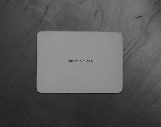 A black-and-white photo of an Oblique Strategy card. The card reads: 'Use an old idea'.