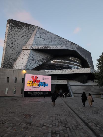 Façade de la Philharmonie de Paris. Sur un écran, l'affiche de l'exposition "Video Games & Music"