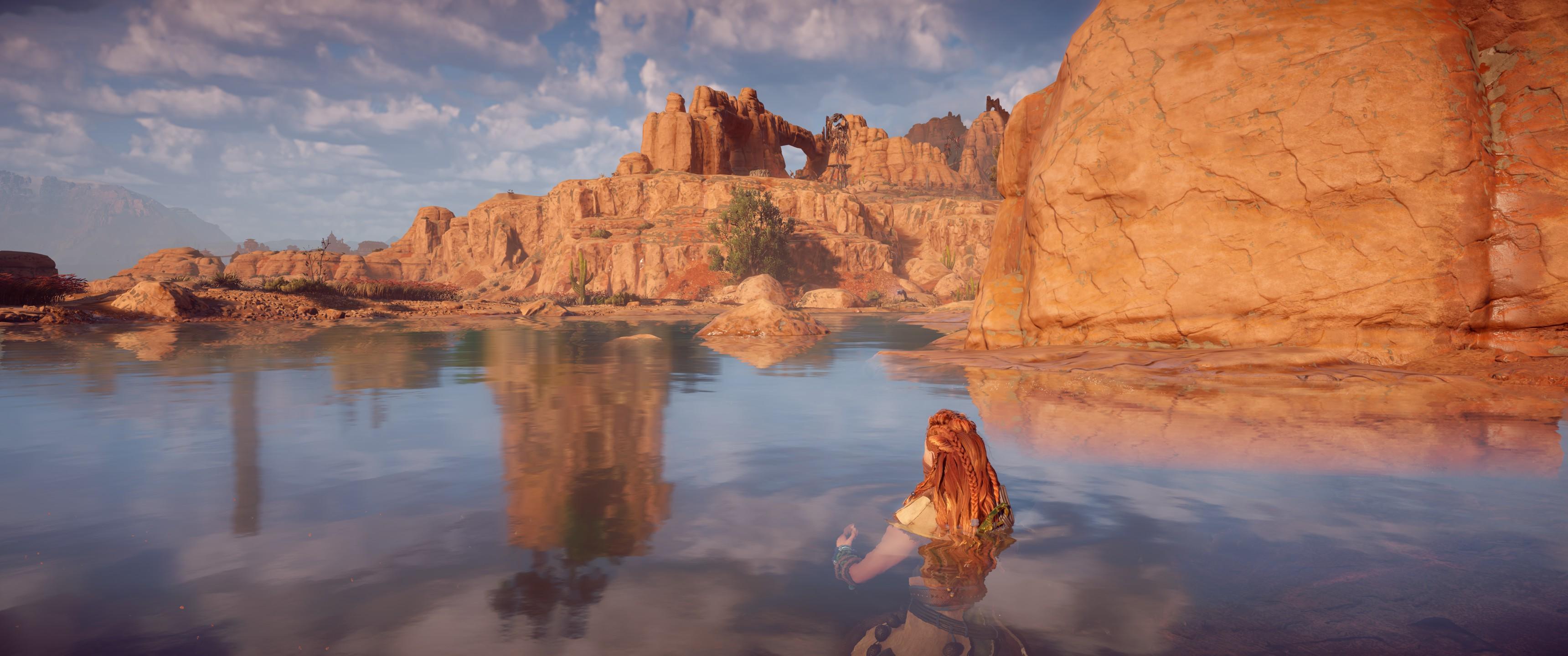 Aloy nage dans un lac. Les reflets de montagnes qu'on voit dans le lac ne correspondent pas du tout au montagne qu'on voit à l'horizon.
