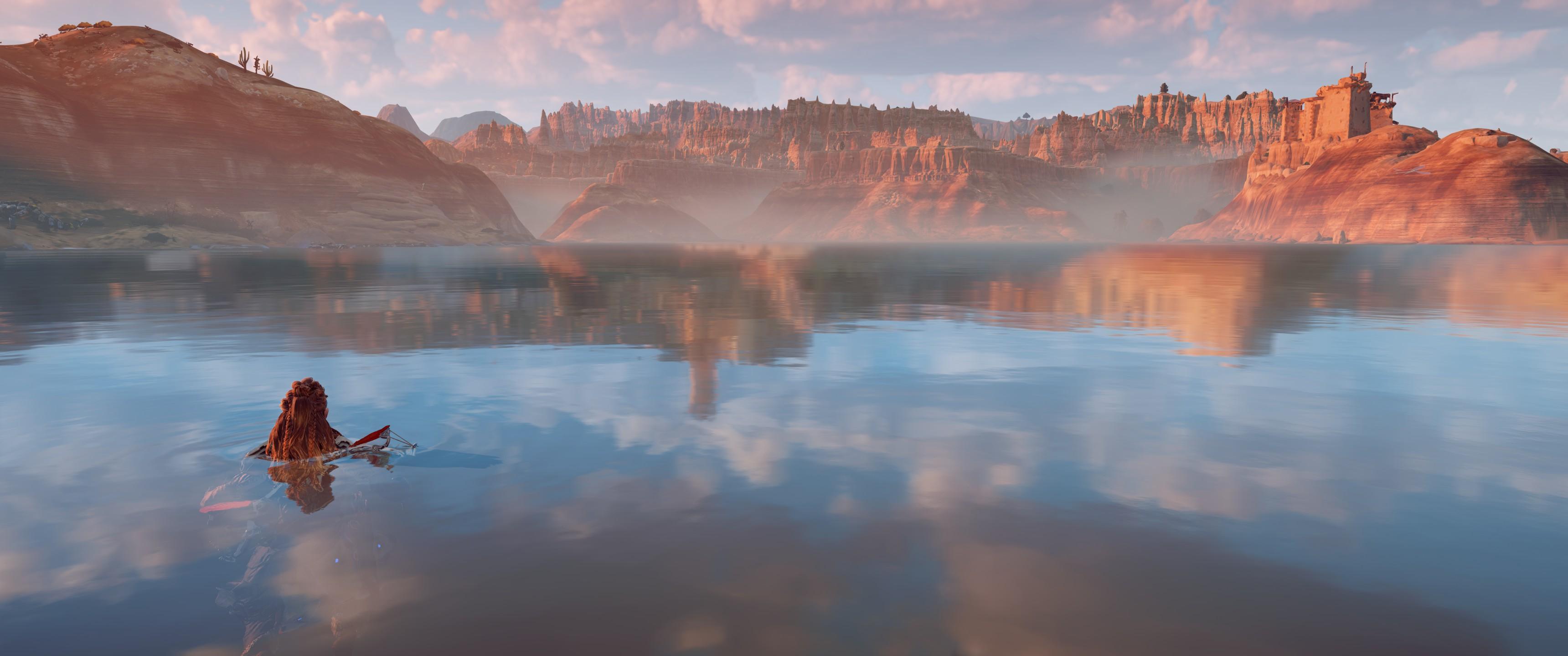 Aloy nage dans un lac. Les reflets de montagnes qu'on voit dans le lac ne correspondent pas du tout au montagne qu'on voit à l'horizon.